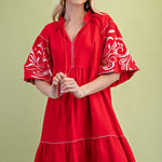 Poppy colored dress. Collared. Tiered detailing. Hits above the knee. Pattern on the short sleeves in white.