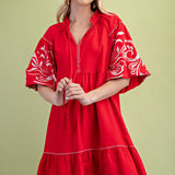 Poppy colored dress. Collared. Tiered detailing. Hits above the knee. Pattern on the short sleeves in white.