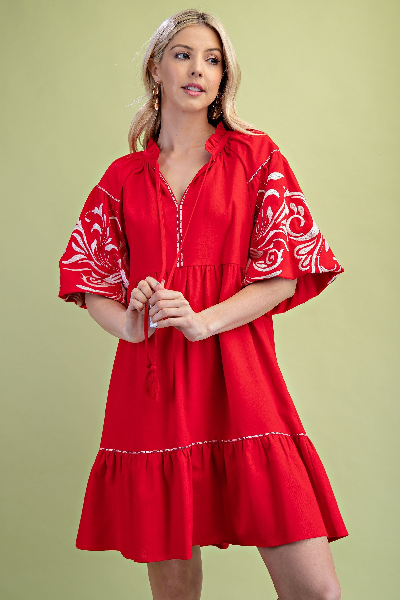 Poppy colored dress. Collared. Tiered detailing. Hits above the knee. Pattern on the short sleeves in white.