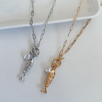 Two gold and silver fish-shaped pendants on chains against a white background