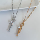 Two gold and silver fish-shaped pendants on chains against a white background