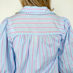 Collared light blue top with pink pin stripes with a touch of white. Button up style. Loose fit. 3/4 length sleeves that have a slight puff look to them.