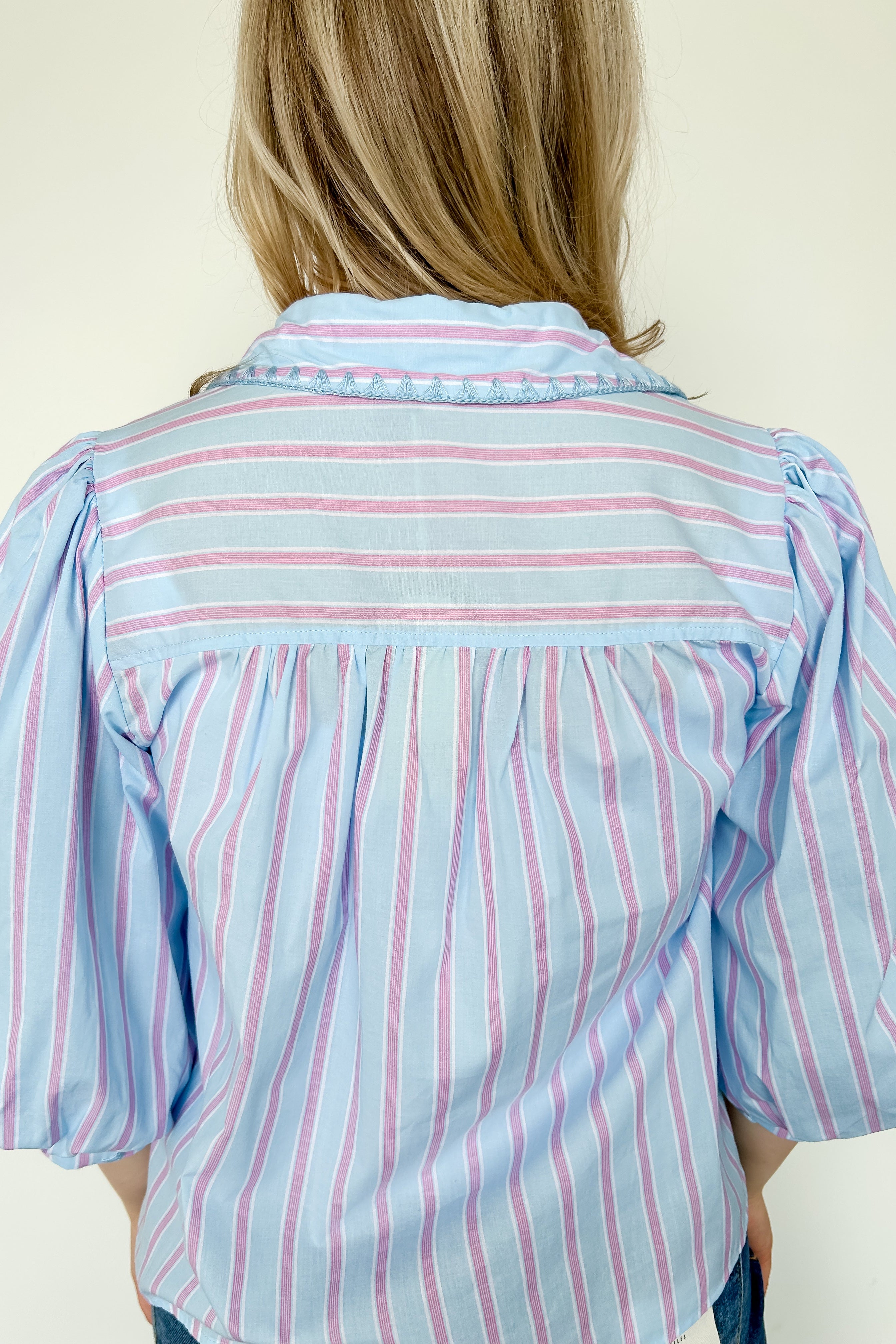 Collared light blue top with pink pin stripes with a touch of white. Button up style. Loose fit. 3/4 length sleeves that have a slight puff look to them.