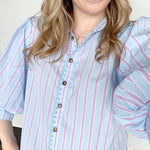 Collared light blue top with pink pin stripes with a touch of white. Button up style. Loose fit. 3/4 length sleeves that have a slight puff look to them.