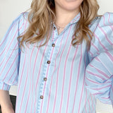Collared light blue top with pink pin stripes with a touch of white. Button up style. Loose fit. 3/4 length sleeves that have a slight puff look to them.