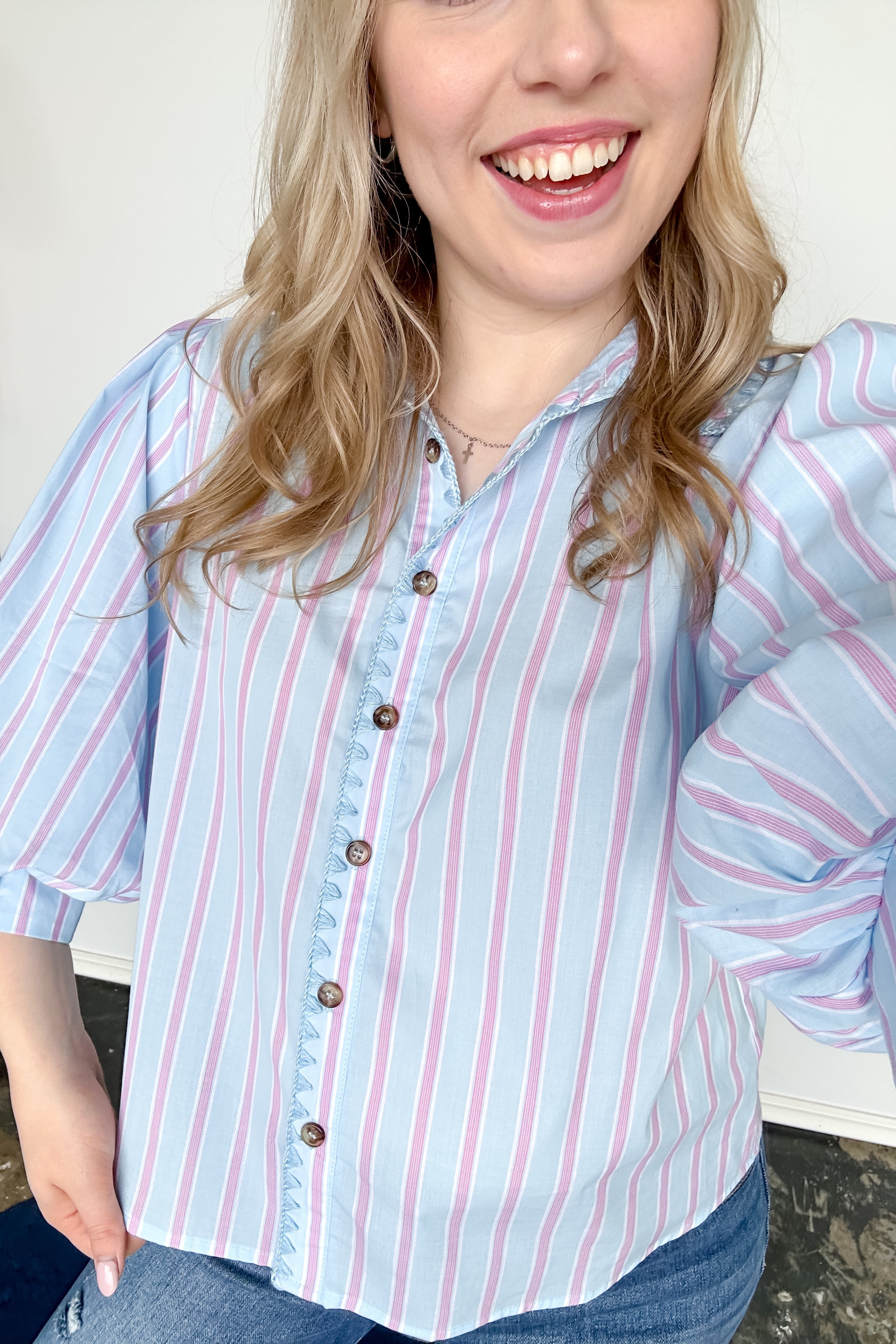 Collared light blue top with pink pin stripes with a touch of white. Button up style. Loose fit. 3/4 length sleeves that have a slight puff look to them.