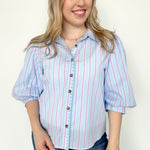Collared light blue top with pink pin stripes with a touch of white. Button up style. Loose fit. 3/4 length sleeves that have a slight puff look to them.