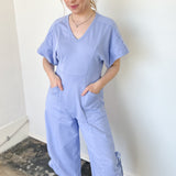 Photo of model wearing a short sleeve, v-neck, chambray blue jumpsuit 