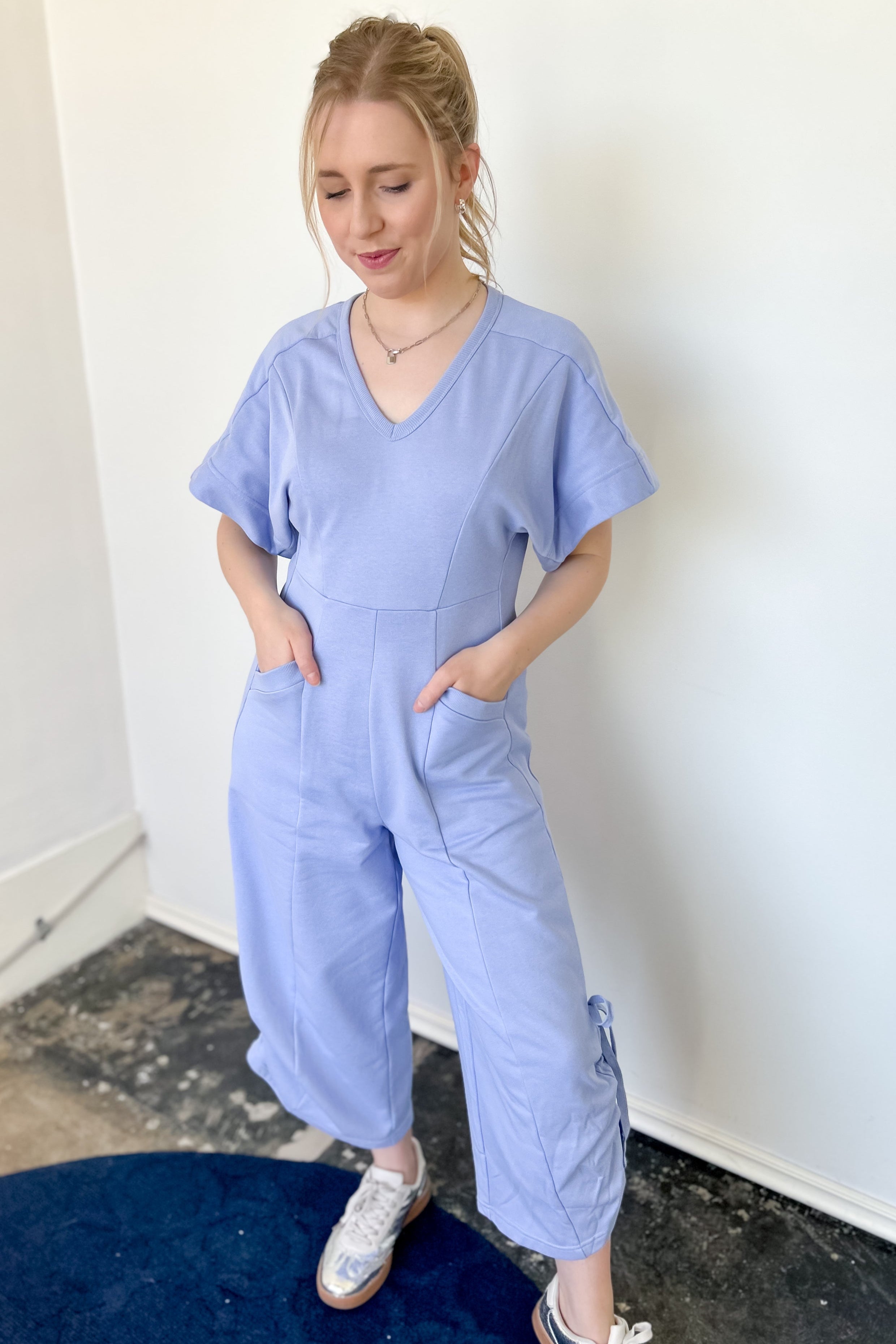 Photo of model wearing a short sleeve, v-neck, chambray blue jumpsuit 