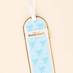 Acrylic bookmark with bow design in packaging on a beige background