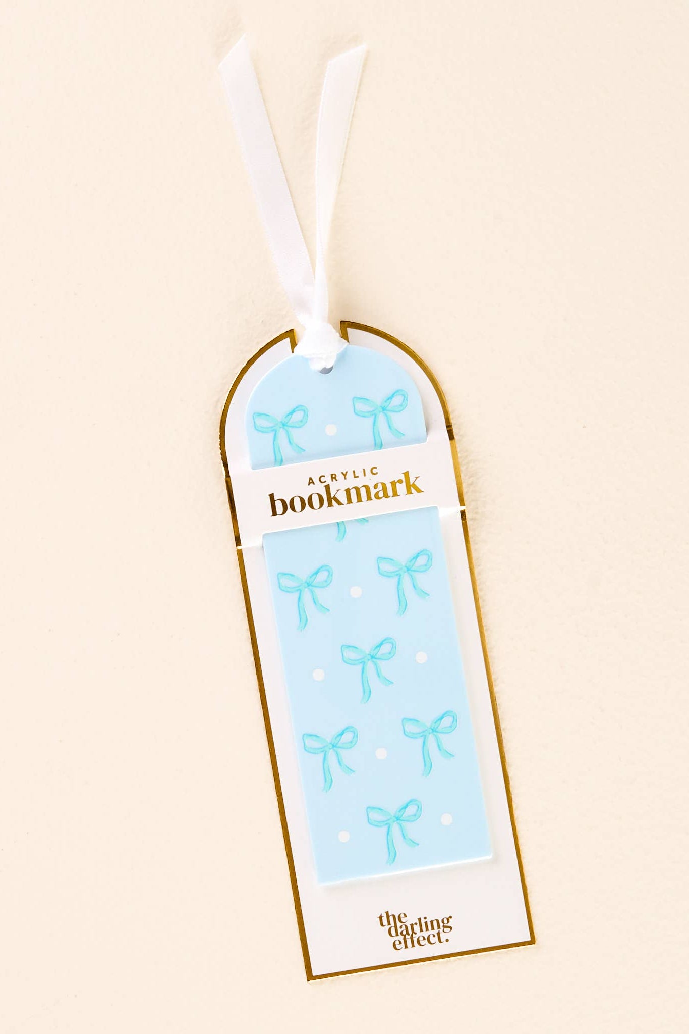 Acrylic bookmark with bow design in packaging on a beige background