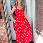 Woman in bright orange polka dot dress that is full length.