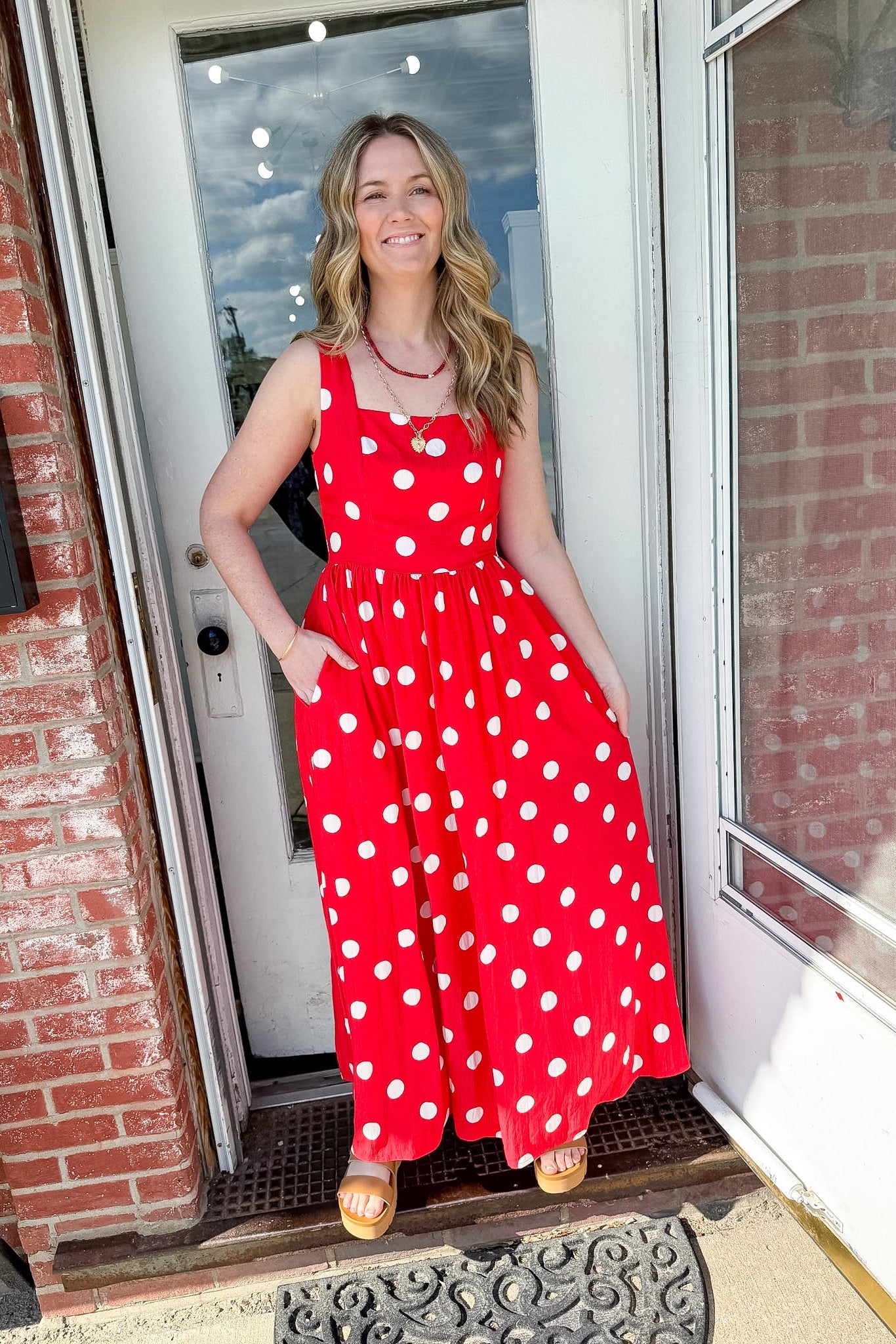 Woman in bright orange polka dot dress that is full length.