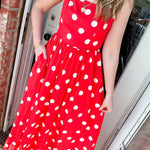 Woman wearing a bright orange dress with white polka dots and two necklaces.