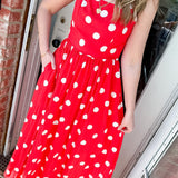 Woman wearing a bright orange dress with white polka dots and two necklaces.