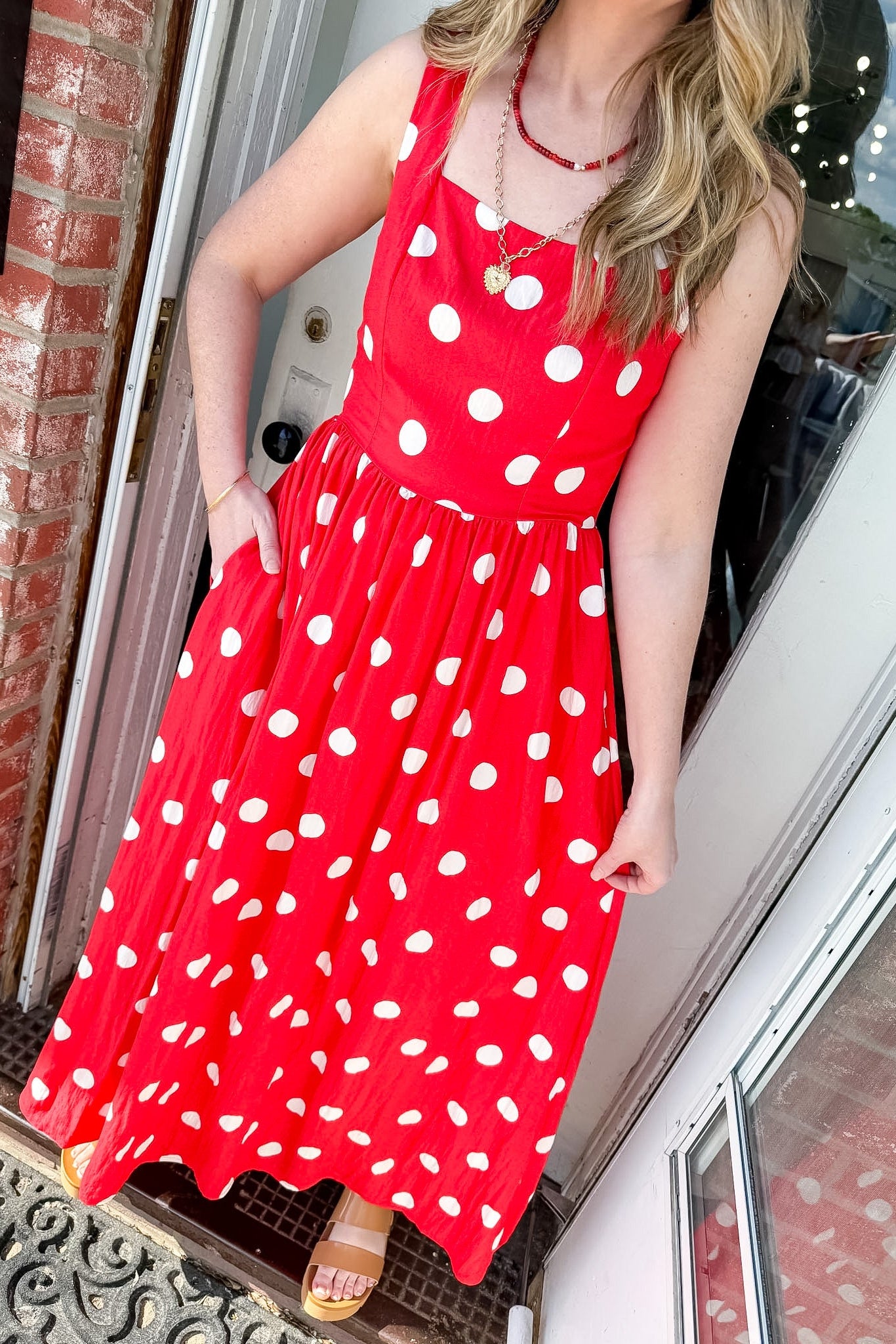 Woman wearing a bright orange dress with white polka dots and two necklaces.