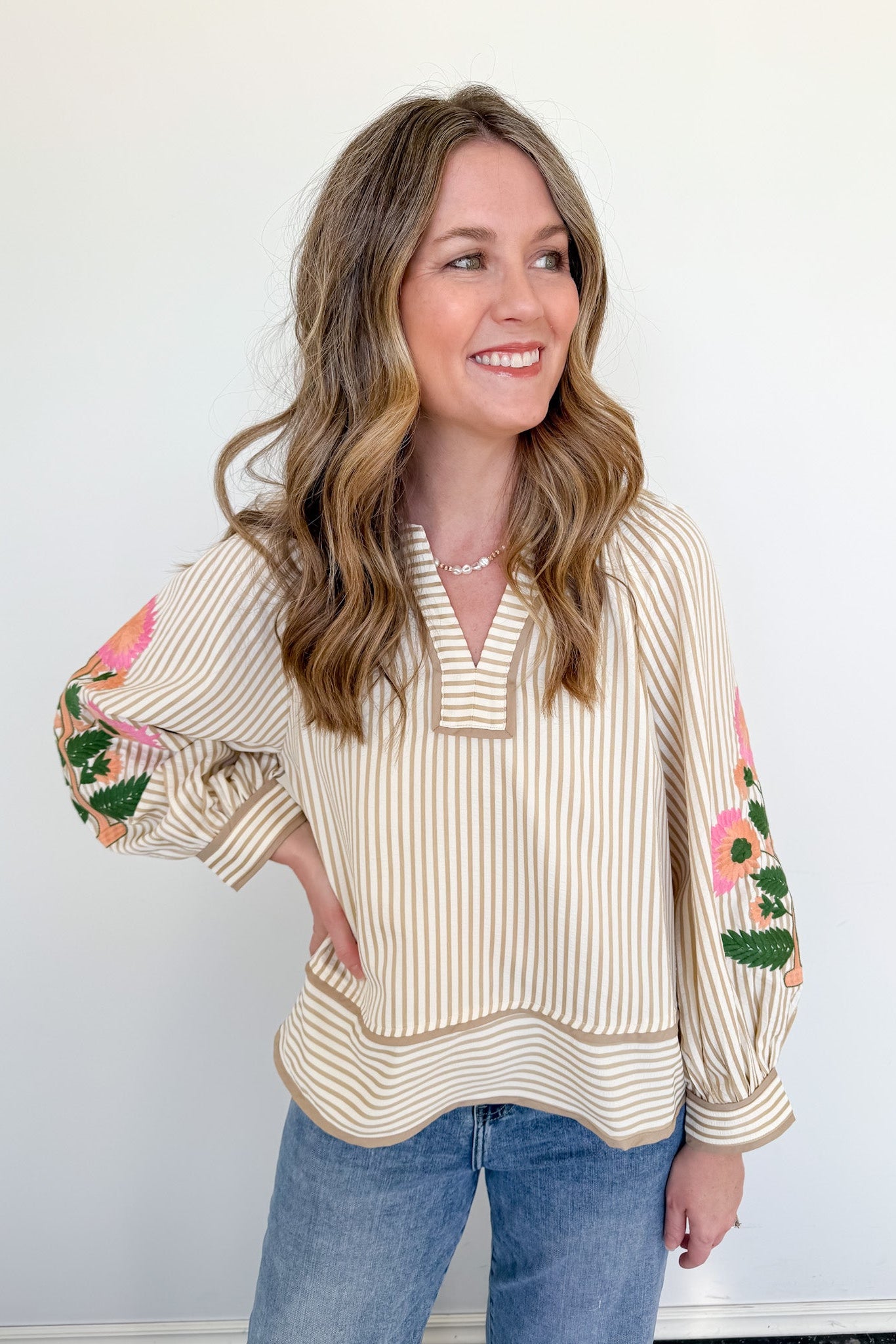 Woman wearing a striped blouse with floral sleeves against a white background