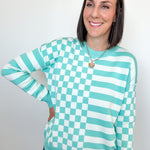 Person wearing a green and white checkered sweater against a plain background