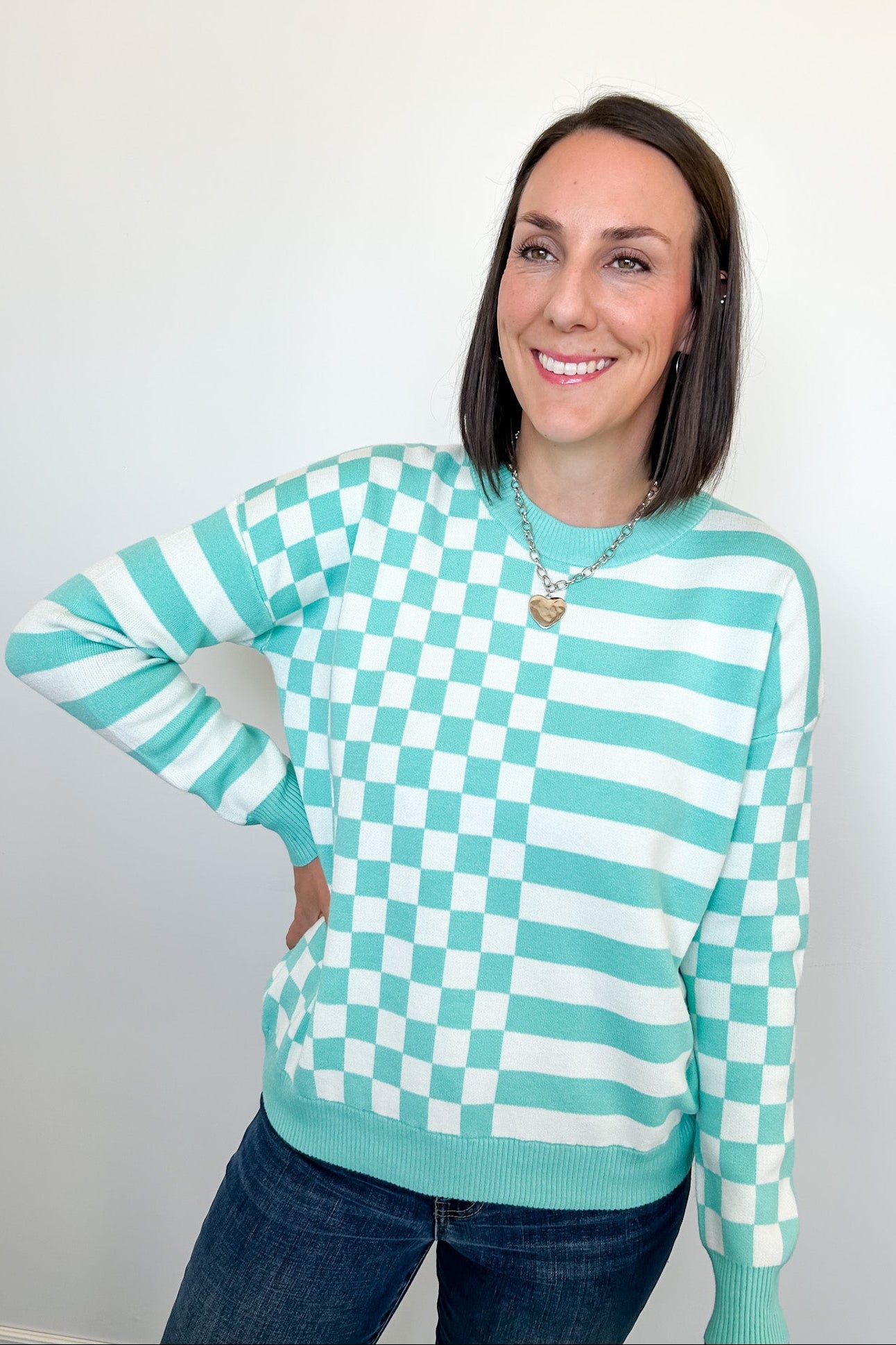 Person wearing a green and white checkered sweater against a plain background