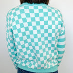 Person wearing a green and white checkered sweater against a plain background