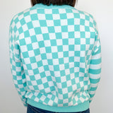 Person wearing a green and white checkered sweater against a plain background