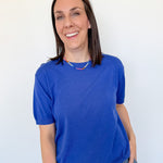 Woman wearing a blue shirt and jeans against a white background
