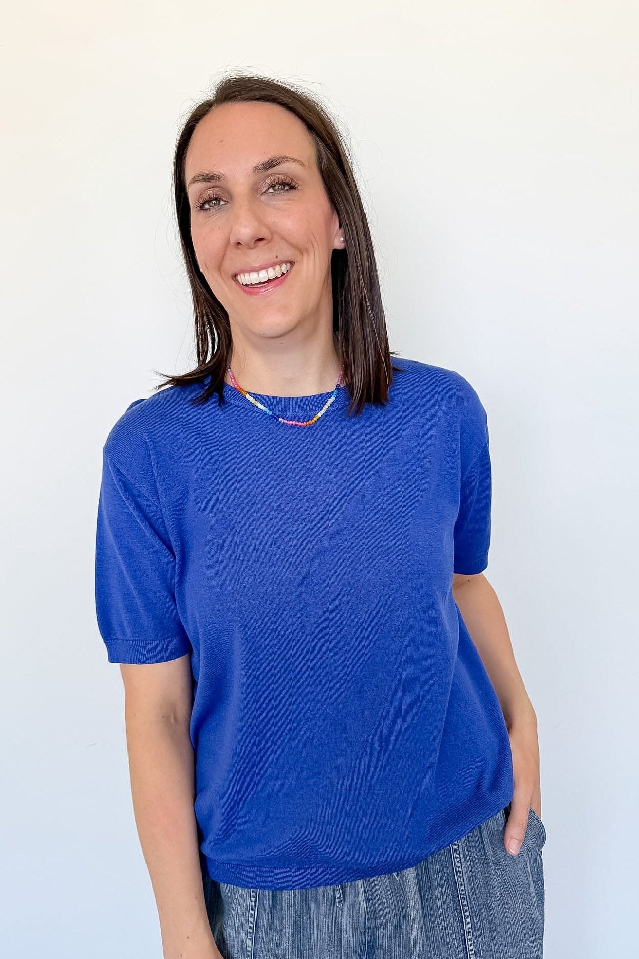 Woman wearing a blue shirt and jeans against a white background