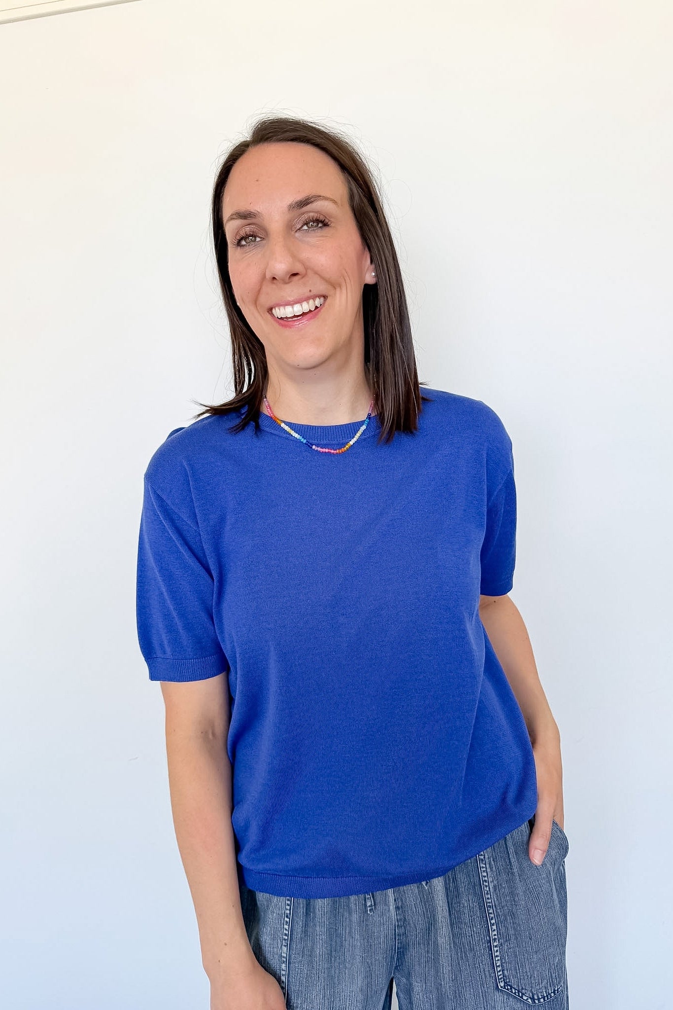 Woman wearing a blue shirt and jeans against a white background
