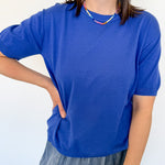 Woman wearing a royal blue sweater with a colorful necklace