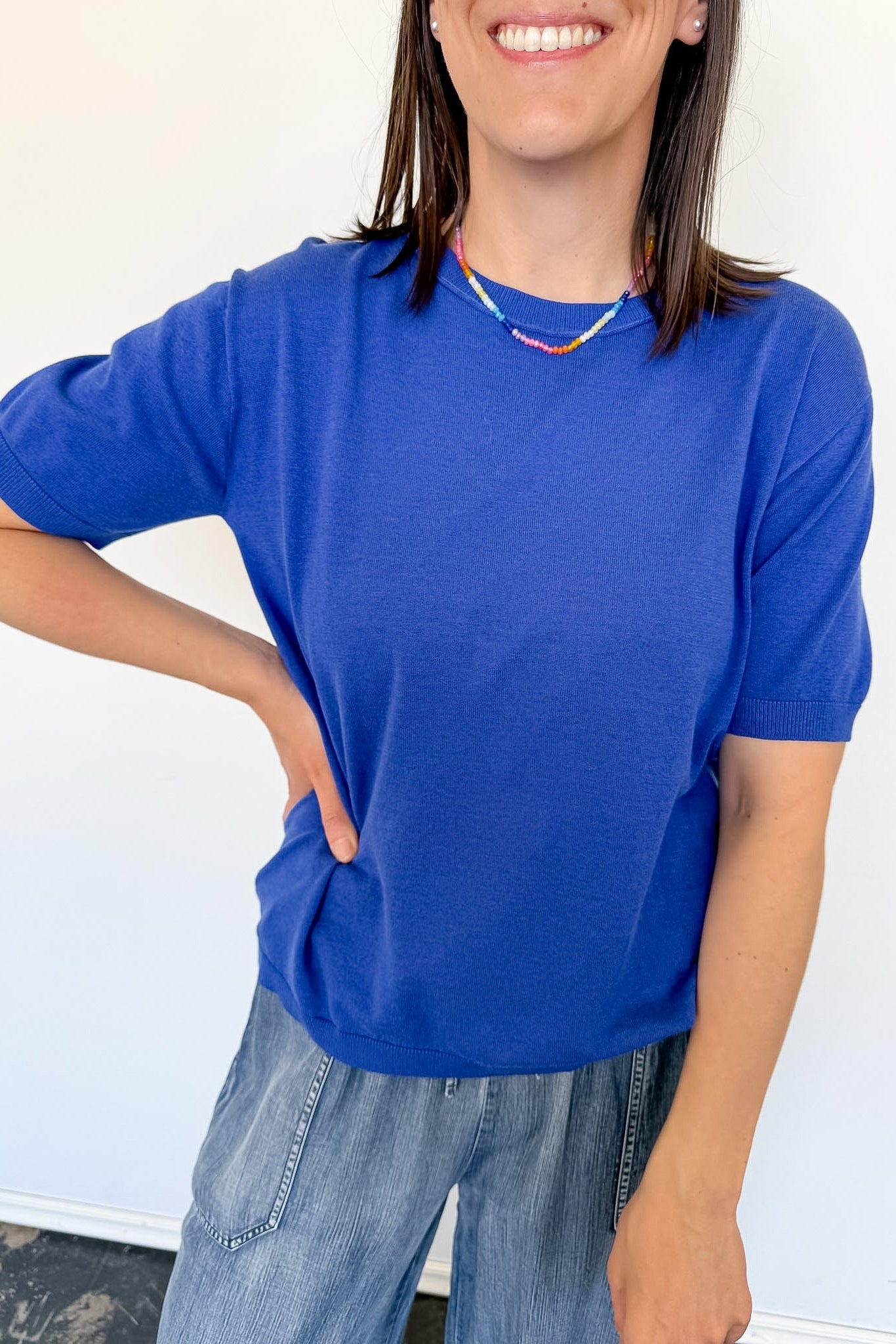 Woman wearing a royal blue sweater with a colorful necklace