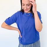 Woman wearing a blue shirt and jeans against a white background