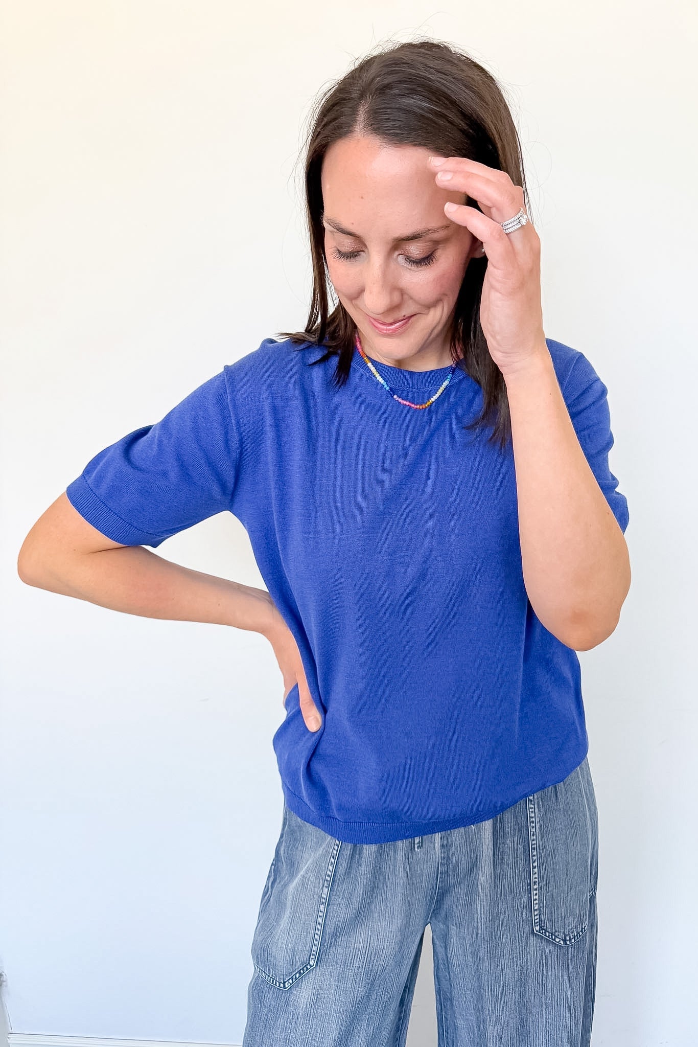 Woman wearing a blue shirt and jeans against a white background