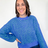 Woman wearing a blue and green patterned sweater against a white background