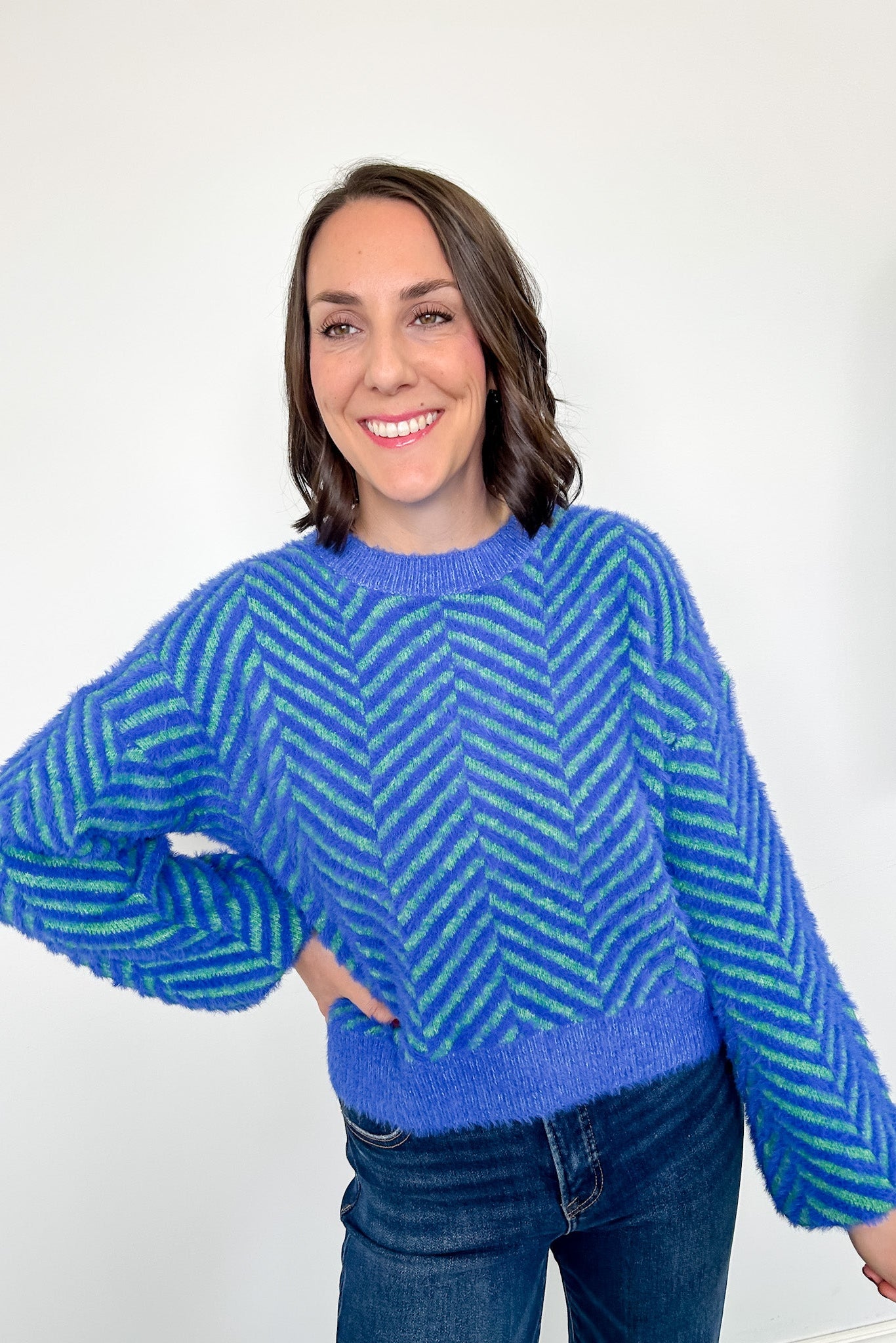 Woman wearing a blue and green patterned sweater against a white background