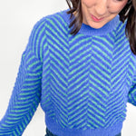 Woman wearing a blue and green striped sweater on a white background