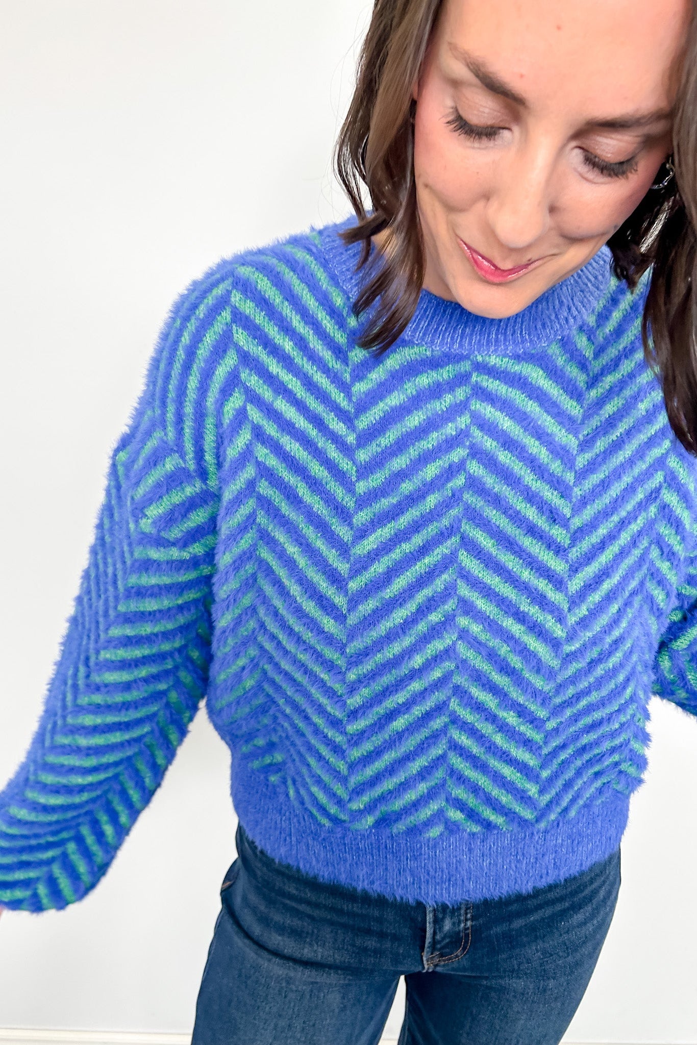 Woman wearing a blue and green striped sweater on a white background