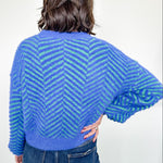 Person wearing a blue and green striped sweater against a white background
