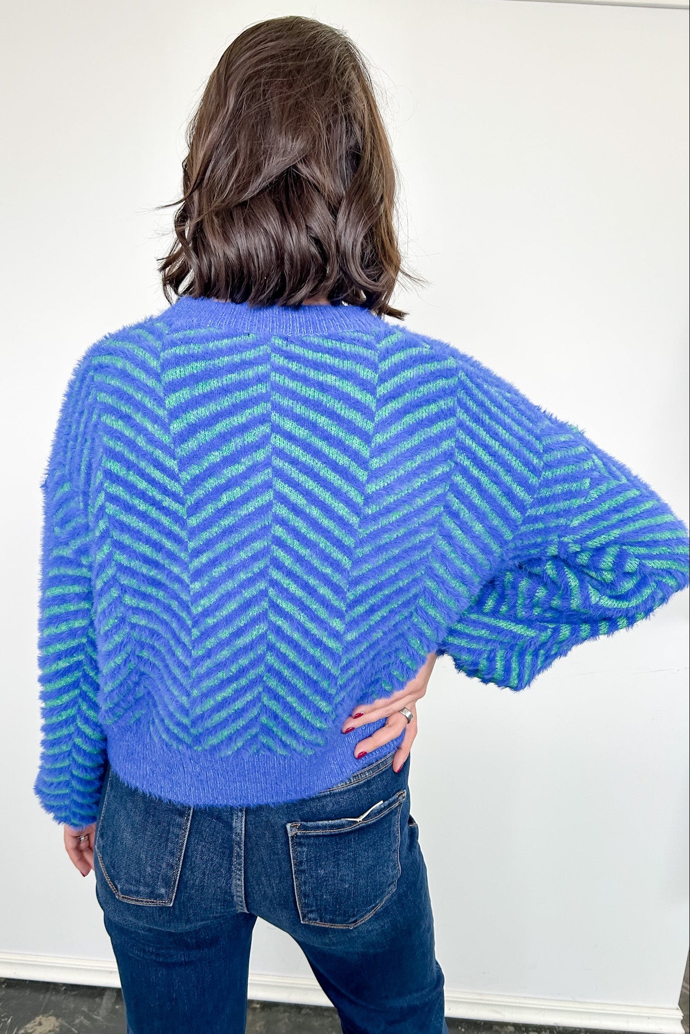 Person wearing a blue and green striped sweater against a white background