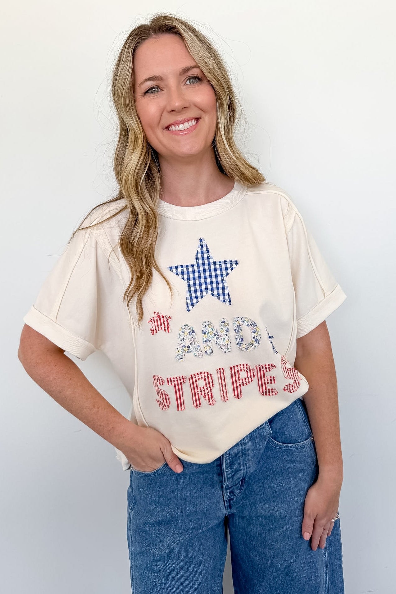 Woman wearing a white t-shirt with a star design and text, standing against a plain background