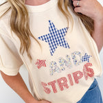 Person wearing a cream-colored t-shirt with a star and text design, standing against a white background.