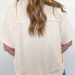 Person wearing a beige blouse and blue jeans against a white background