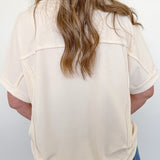 Person wearing a beige blouse and blue jeans against a white background