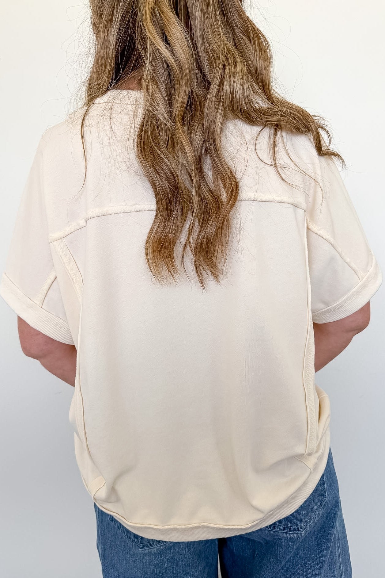 Person wearing a beige blouse and blue jeans against a white background