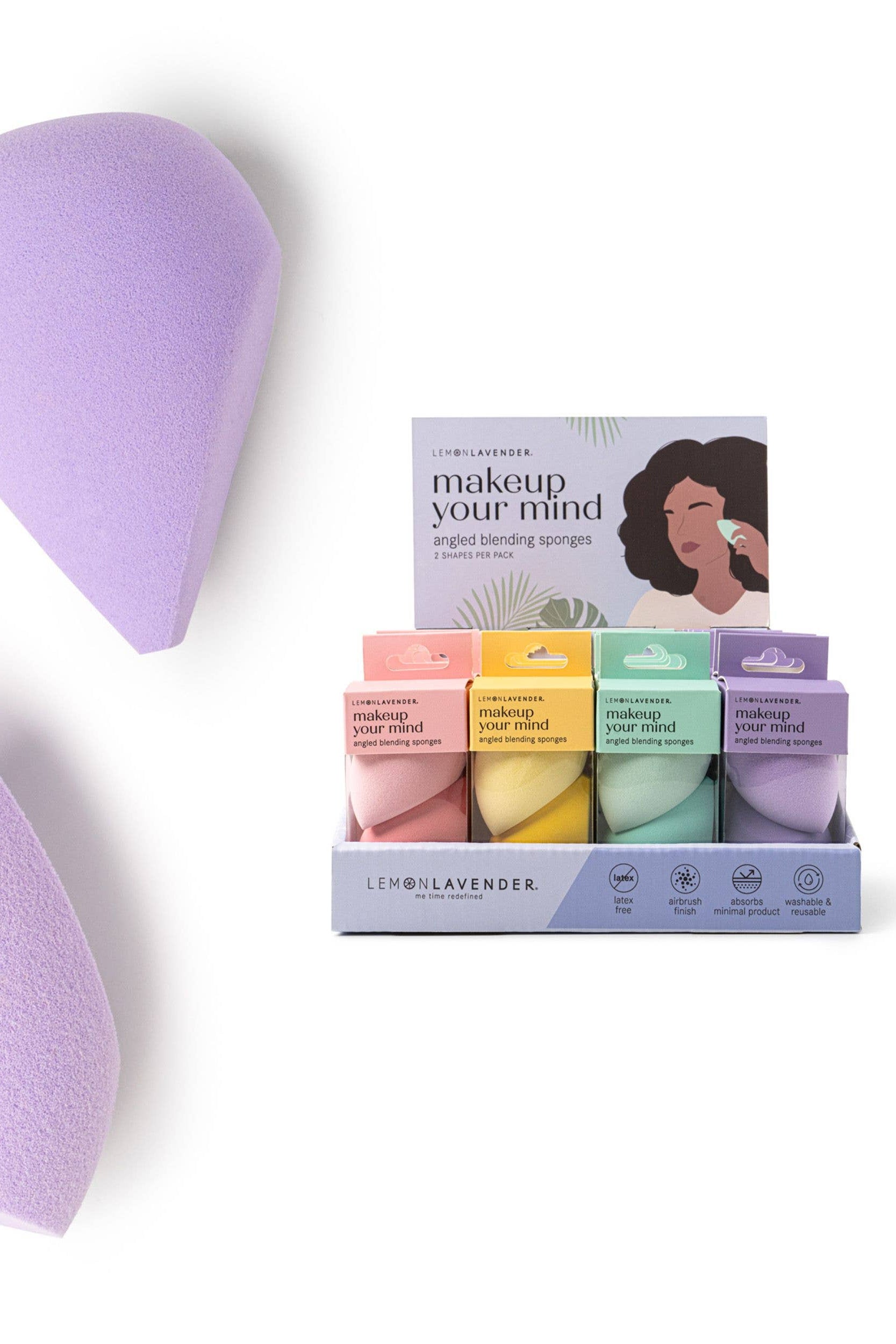 Two purple makeup sponges with a box of additional sponges on a white background