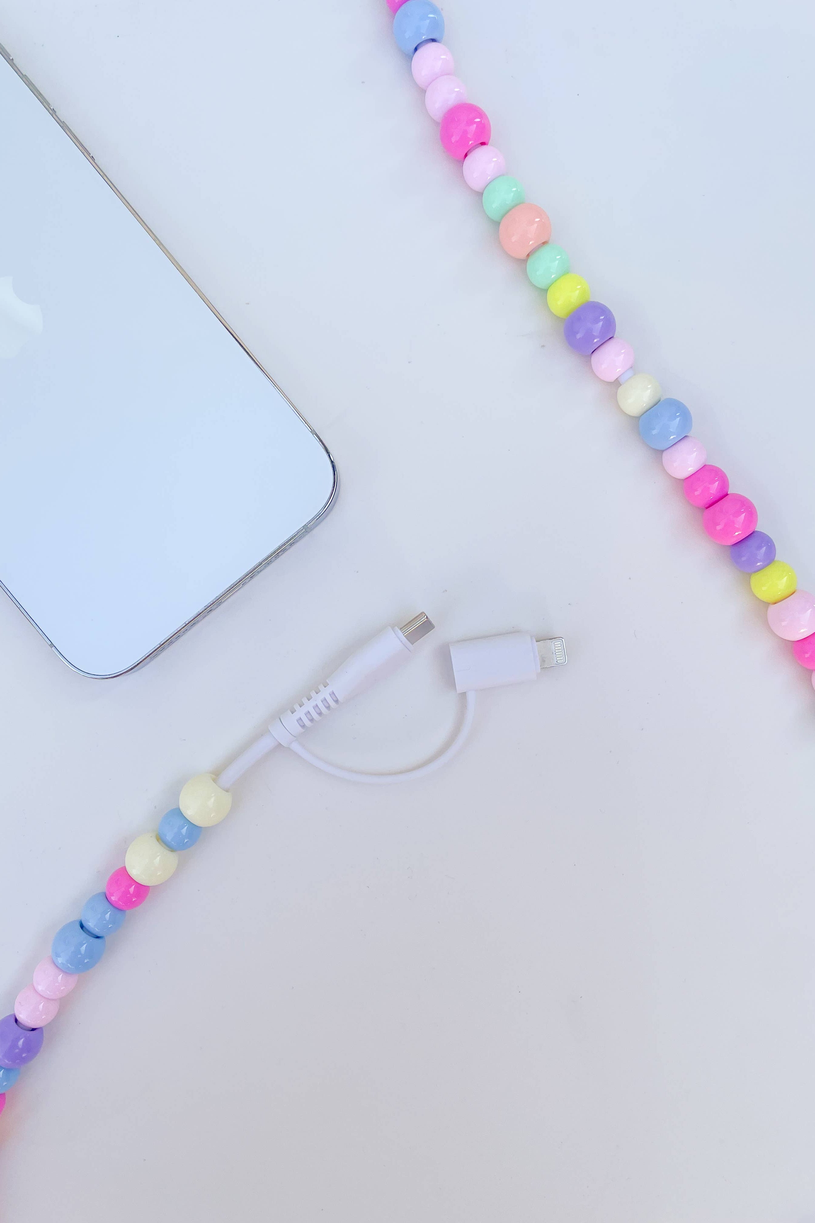 Colorful beaded phone charger on a light surface with a phone in the background