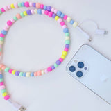 Colorful beaded phone charger next to a smartphone on a white background