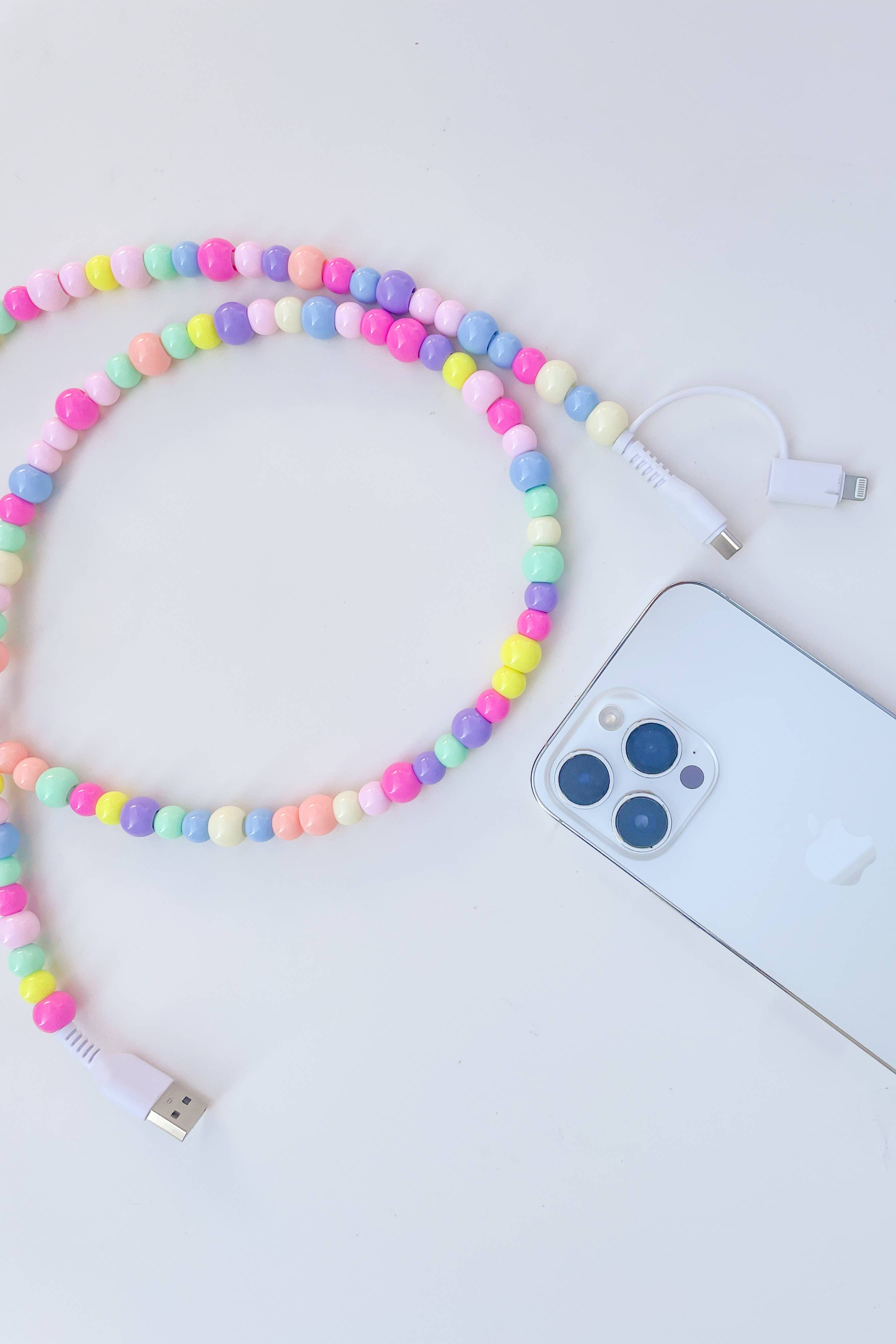 Colorful beaded phone charger next to a smartphone on a white background