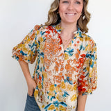 Woman wearing a colorful floral blouse against a white background