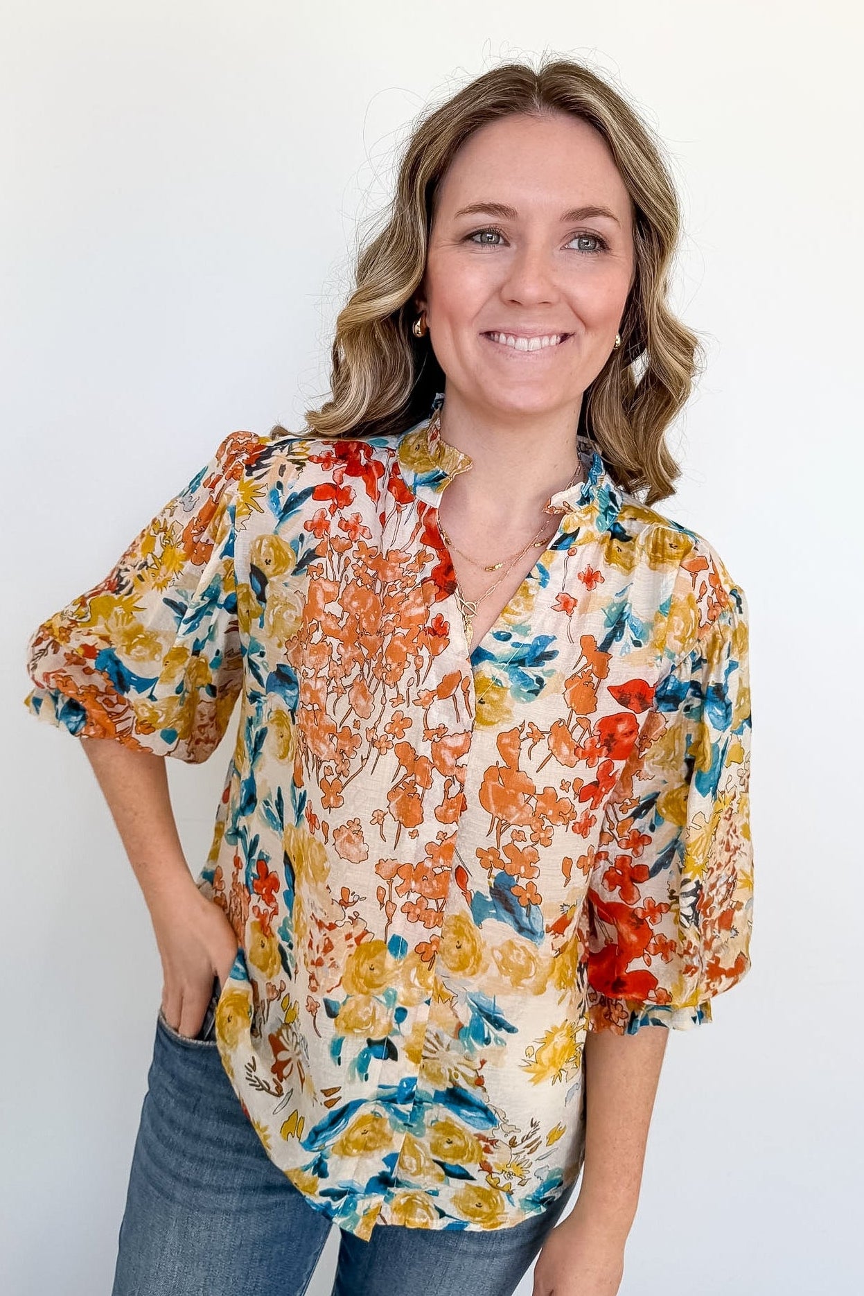 Woman wearing a colorful floral blouse against a white background