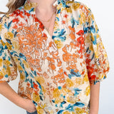 Woman wearing a colorful floral blouse against a white background